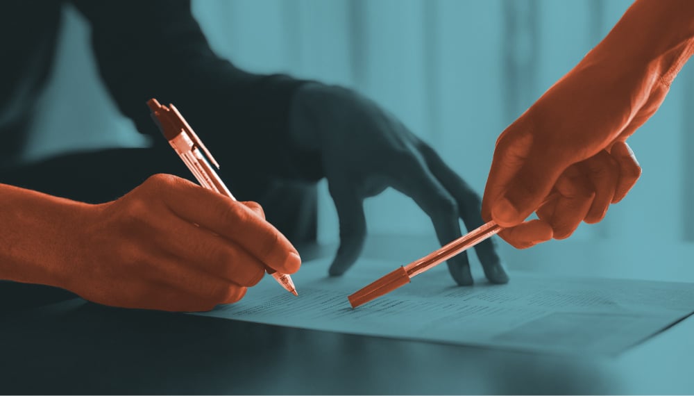 Two people pointing at documents on a table using pens